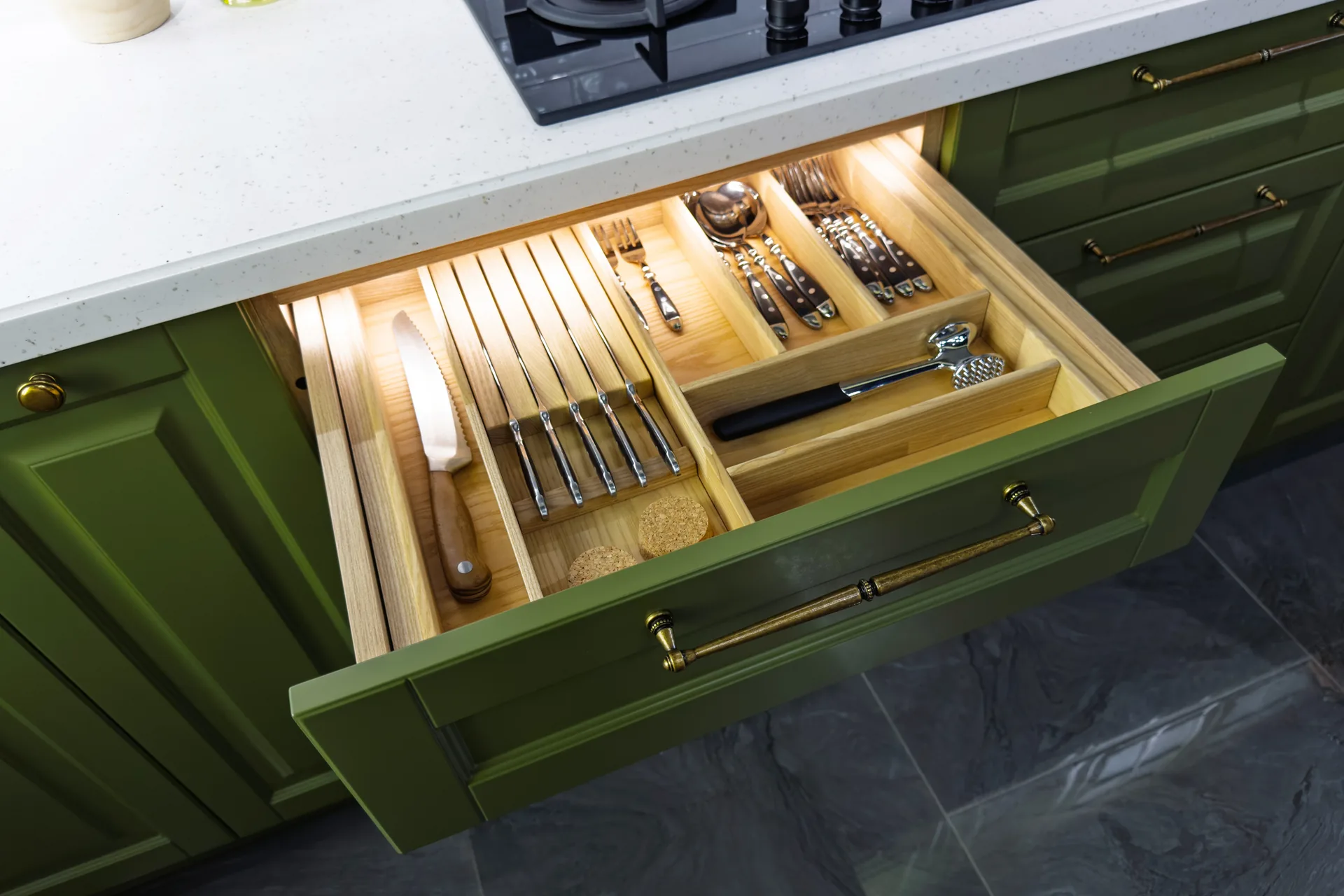 Lit oak cutlery drawer in a green kitchen
